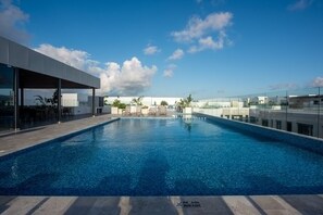 Ein moderner Pool auf dem Dachboden mit klarem, blauem Wasser, umgeben von Glaswänden und einem zeitgemäßen Gebäude.
