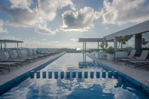 Ein Poolbereich mit Liegestühlen und freiem Blick auf das Meer.