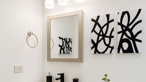 Ein Badezimmer mit einem weißen Waschbecken, einer Toilette und abstrakter Wandgestaltung.