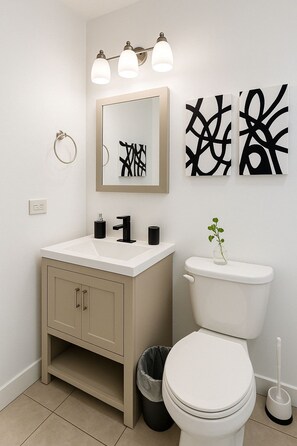 Een badkamer met een witte wastafel, toilet en abstracte wanddecoratie.