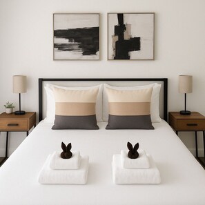 Een hotelkamer met een groot bed, twee nachtkastjes, twee lampen en twee abstracte schilderijen aan de muur.