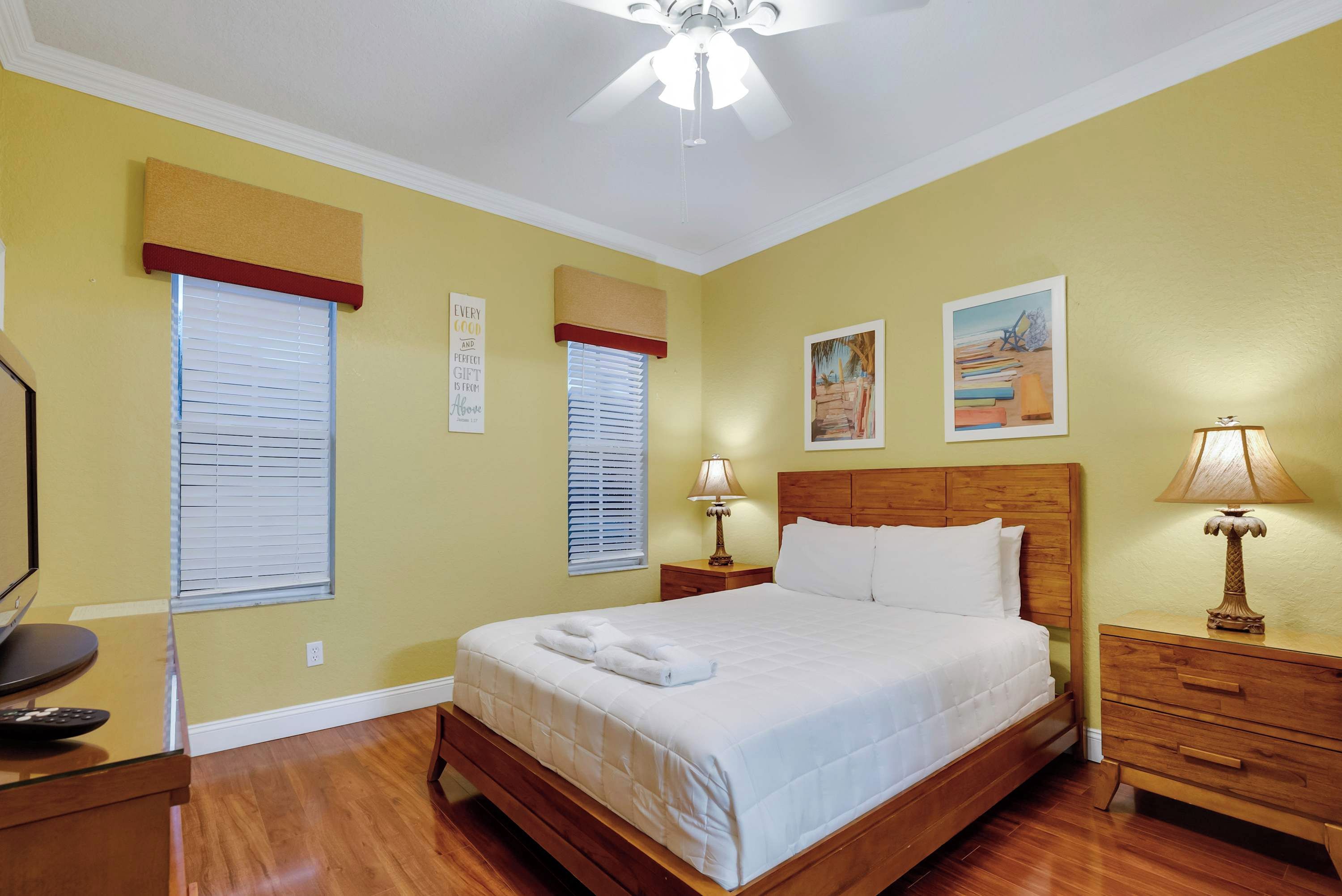 Habitación de hotel con cama, mesitas de noche, lámpara y cuadros en las paredes.