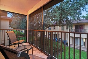Ein Balkon mit Stuhl und Tisch, mit Blick auf ein Wohngebiet mit Häusern und Bäumen.