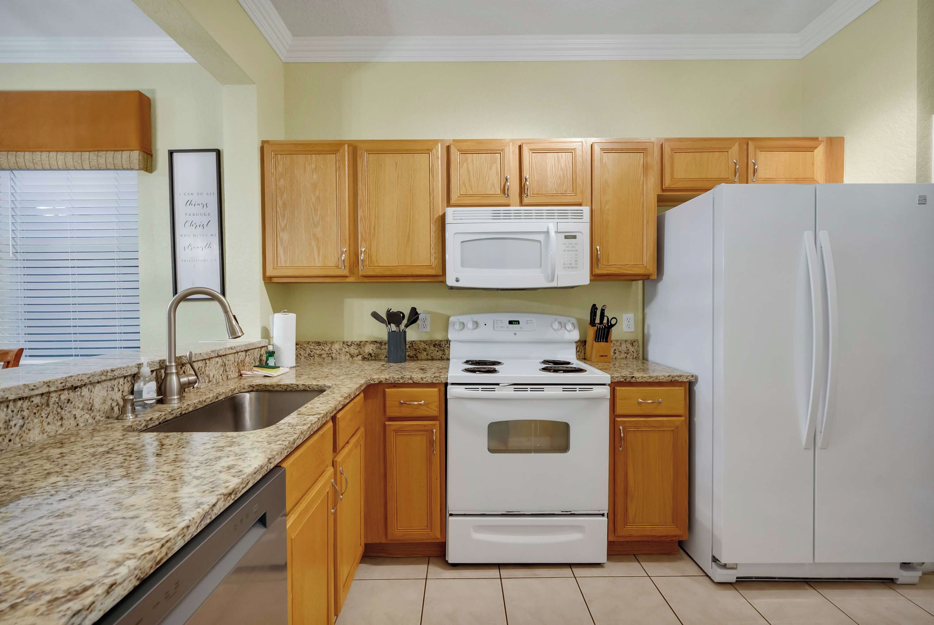 A kitchen with wooden cabinets, a white stove, a microwave, and a refrigerator.
