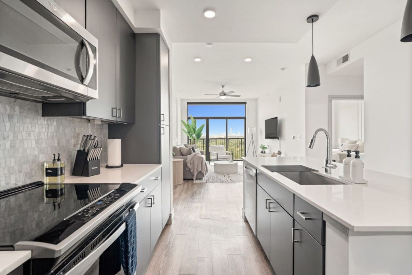 A modern kitchen with a large island, built-in appliances, and a view to the outdoors.