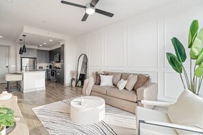 A modern living room with a sofa, coffee table, and a large mirror. - Near NRG-Reliant, TMC, Downtown | Fast Wi-Fi (Houston)