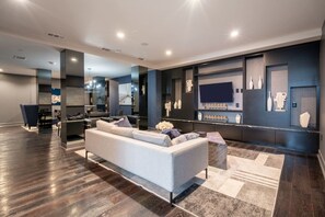 A modern living room with a sofa, a coffee table, and a TV mounted on the wall. - Near NRG-Reliant, TMC, Downtown | Fast Wi-Fi (Houston)