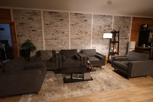 Sala de estar con pared de ladrillo, dos sofás, una mesa de centro y una lámpara.