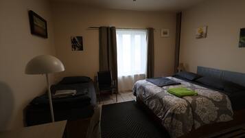 Un dormitorio con una cama, una silla, un escritorio y una lámpara.