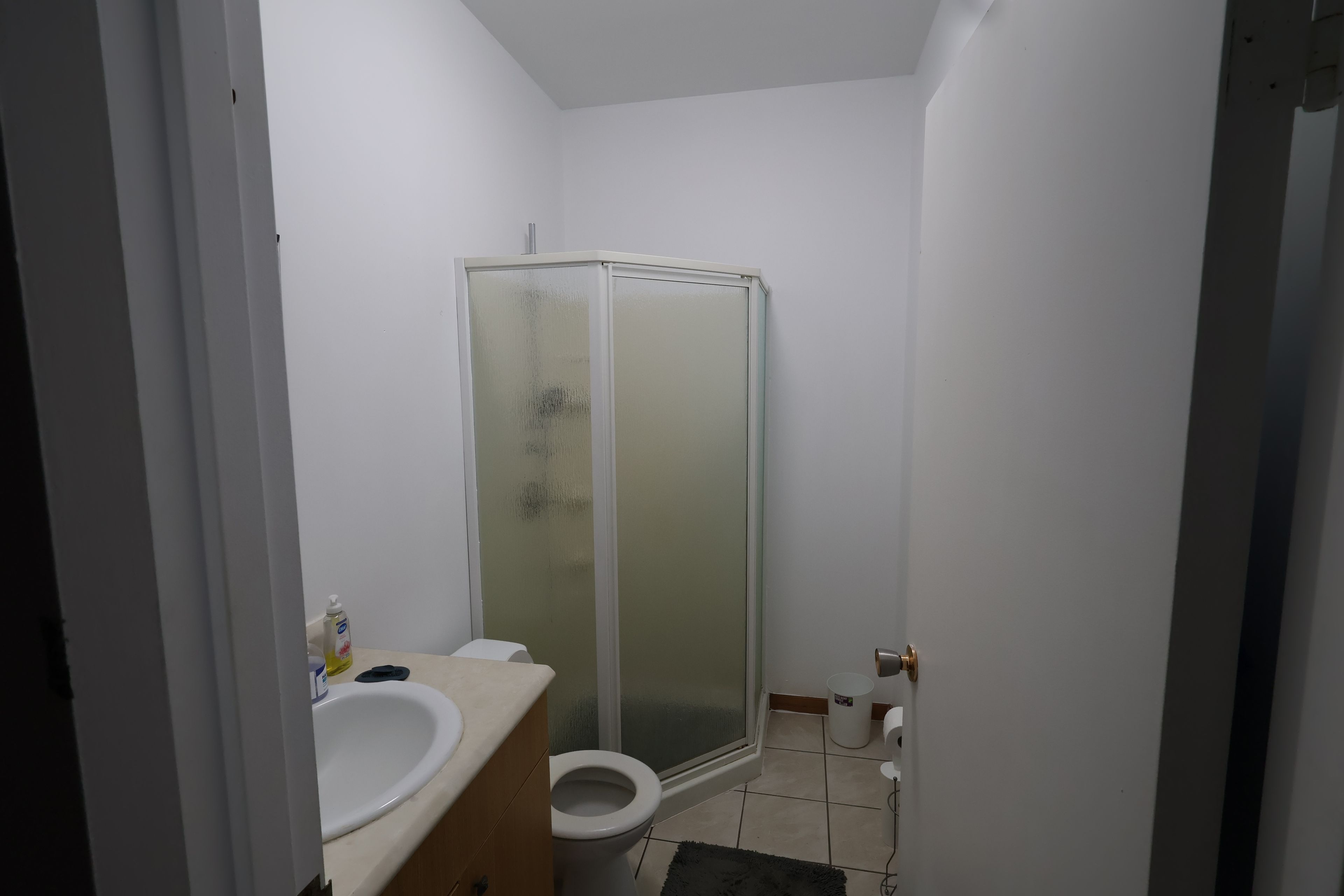 Un baño con inodoro, lavamanos y ducha con mampara de vidrio.