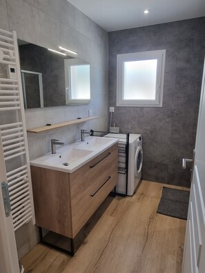 A modern bathroom with a double sink vanity, a built-in washing machine, and a window. - Léontine's Granjou (Ladinhac)