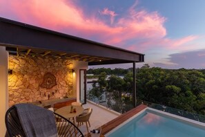 A rooftop terrace with a stone wall, a pool, and a table with chairs. - Ixchel Luxury PH Studio Priv Rooftop Pool 150 Wifi (Tulum)