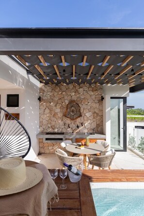 A modern outdoor patio with a stone wall, a dining table, and chairs. - Ixchel Luxury PH Studio Priv Rooftop Pool 150 Wifi (Tulum)