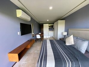 A modern hotel room with a bed, bedside table, lamp, and a flat-screen TV mounted on the wall. - Best Location Studio Steps to the Beach (Playa del Carmen)