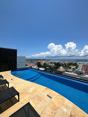 A swimming pool with a view of a cityscape and the ocean. - Best Location Studio Steps to the Beach (Playa del Carmen)