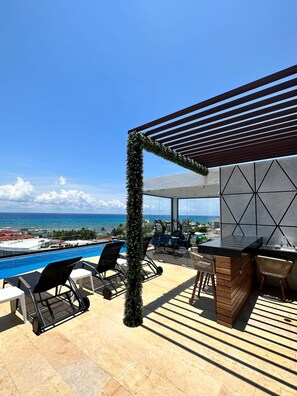 An outdoor terrace with a pool, seating, and a view of the ocean. - Best Location Studio Steps to the Beach (Playa del Carmen)