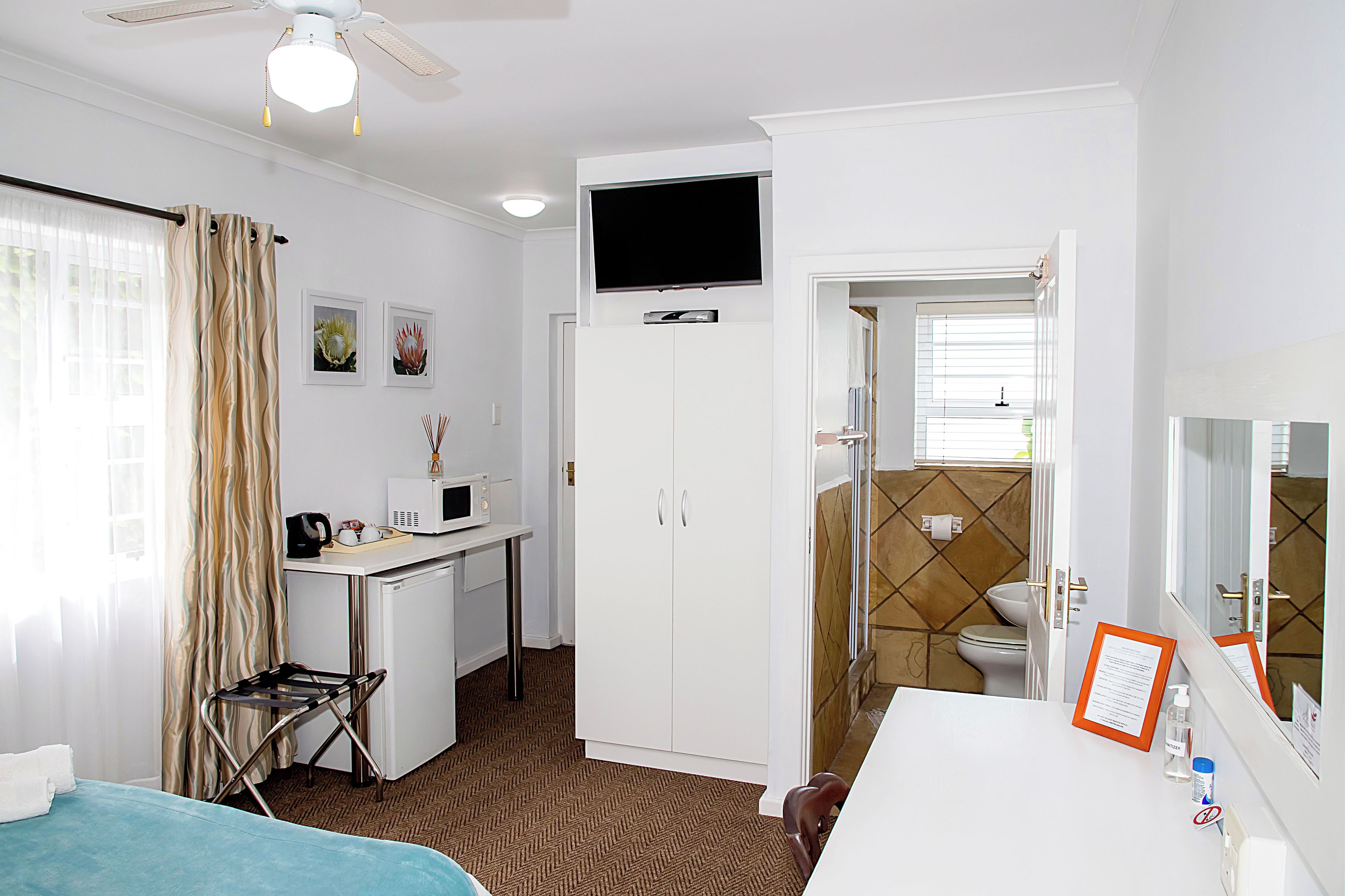 A hotel room with a bed, desk, chair, television, and a bathroom.