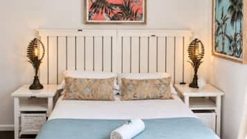 A bedroom with a bed, two nightstands, a ceiling fan, and two wall-mounted lamps.