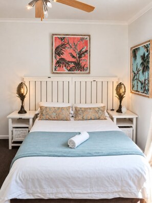 A bedroom with a bed, two nightstands, a ceiling fan, and two wall-mounted lamps. - Abalone Guesthouse (Gqeberha)