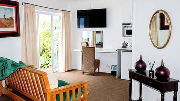 Una habitación con cama, escritorio, televisor, espejo y una mesita con adornos.