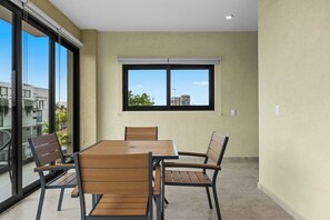 A dining area with a table and chairs, a window with a view of buildings, and a ceiling light. - The boardwalk Nest 1 Block to Malecon & Ocean (Puerto Vallarta)