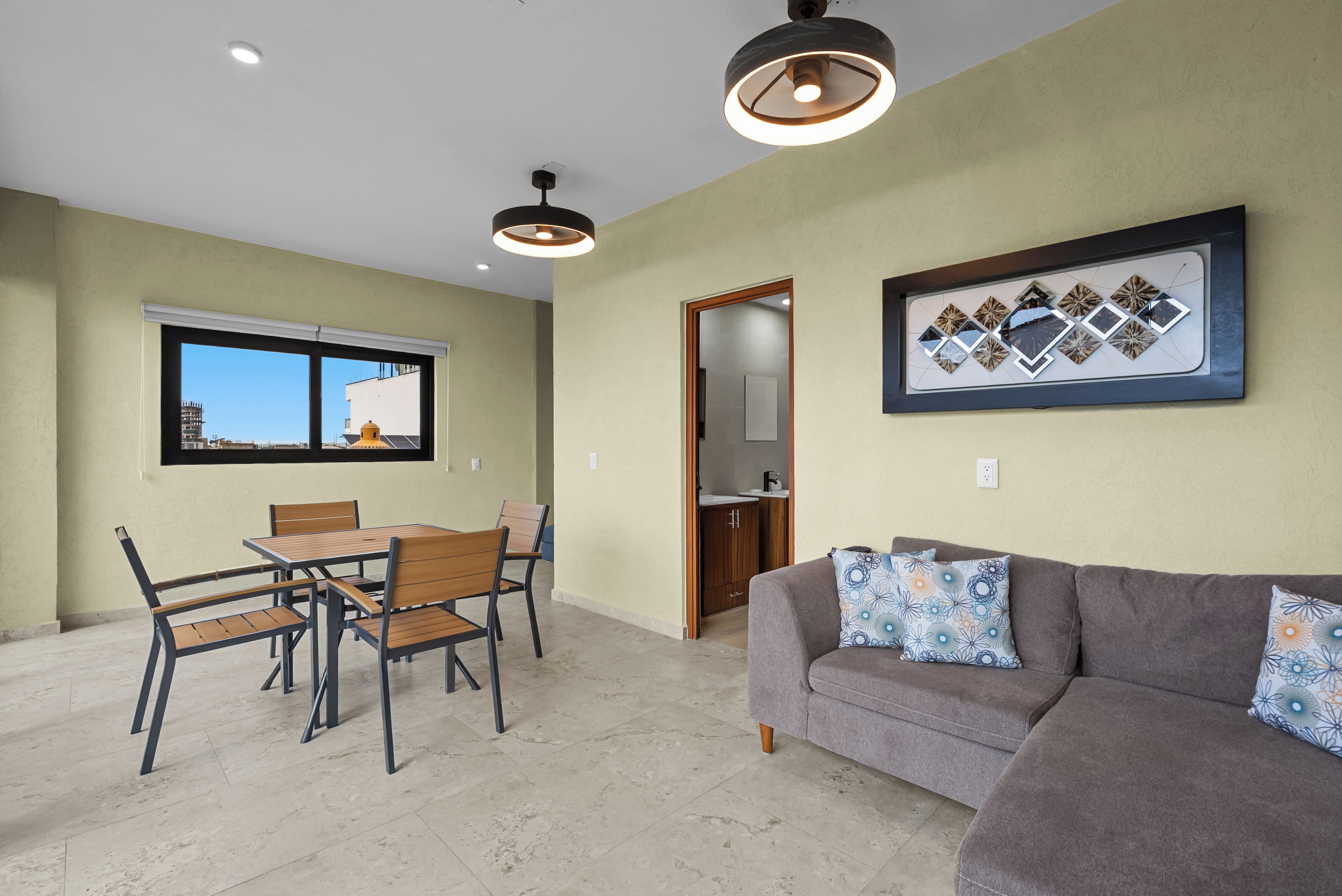 Una sala de estar con un sofá gris y una zona de comedor con mesa y sillas de madera.
