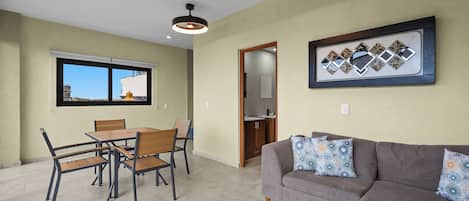 Una sala de estar con un sofá gris y una zona de comedor con mesa y sillas de madera.