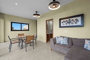 A living room with a gray sofa and a dining area with a wooden table and chairs. - The boardwalk Nest 1 Block to Malecon & Ocean (Puerto Vallarta)