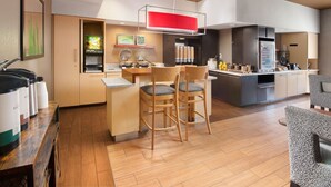 Une cuisine moderne avec un coin repas, des chaises en bois, un comptoir-bar et un réfrigérateur.
