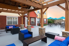 An outdoor patio area with wicker furniture, stone pillars, and a covered seating area. - TownePlace Suites Fort Worth SW/TCU 1BR Suite (Fort Worth)