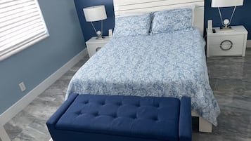 A bedroom with a bed, two bedside tables, a nightstand, a lamp, and a bench.