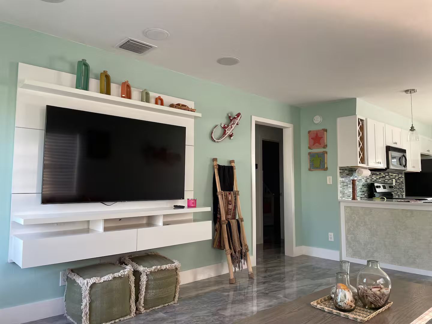 A living room with a flat-screen TV, a painting, and a guitar leaning against the wall.