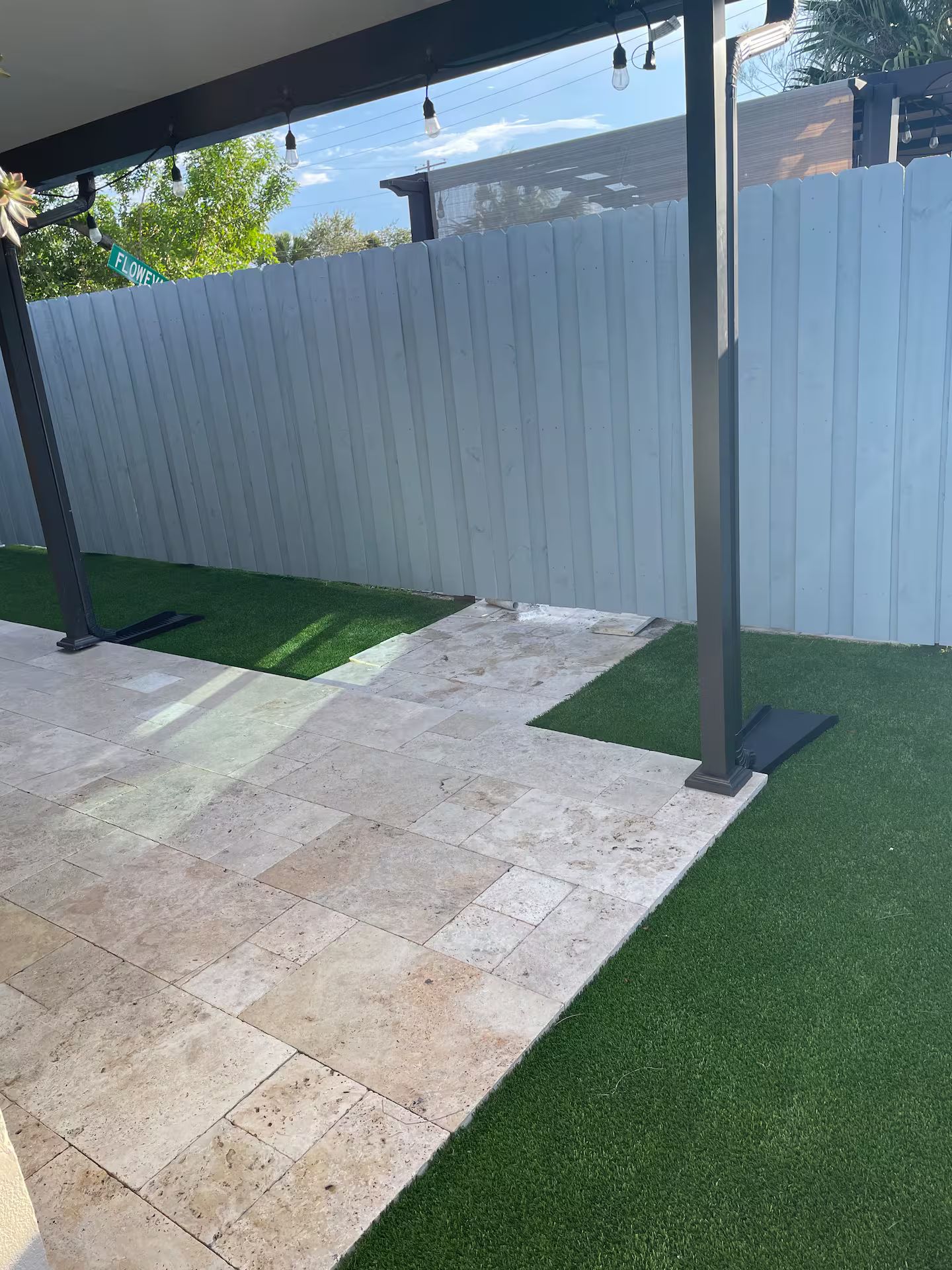 A covered patio area with artificial grass and stone tiles.