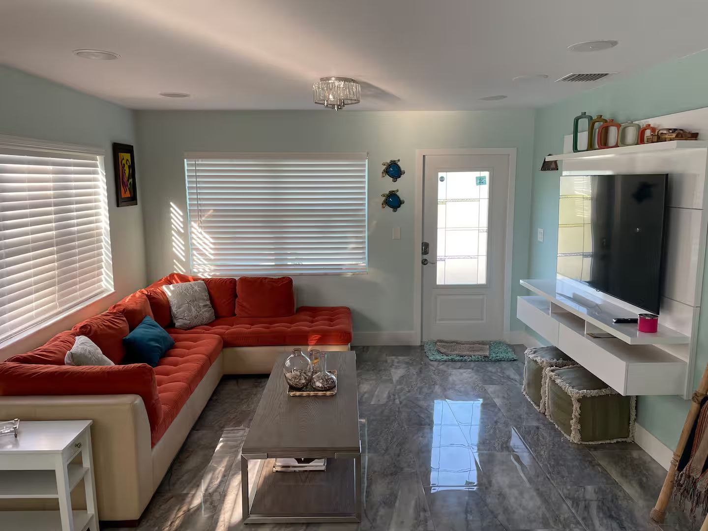 A living room with a sectional sofa, a flat-screen TV, a coffee table, and a door with a frosted glass window.