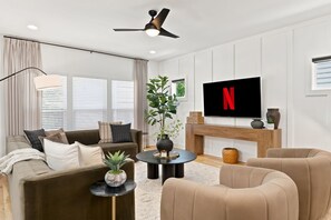 A modern living room with a flat-screen TV, a ceiling fan, and a fireplace. - Nashville Dream Home - Near Downtown, Broadway, Midtown and Much More! (Nashville)