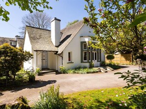 Ein zweigeschossiges Haus mit Satteldach, einer Veranda und einem gepflegten Garten.