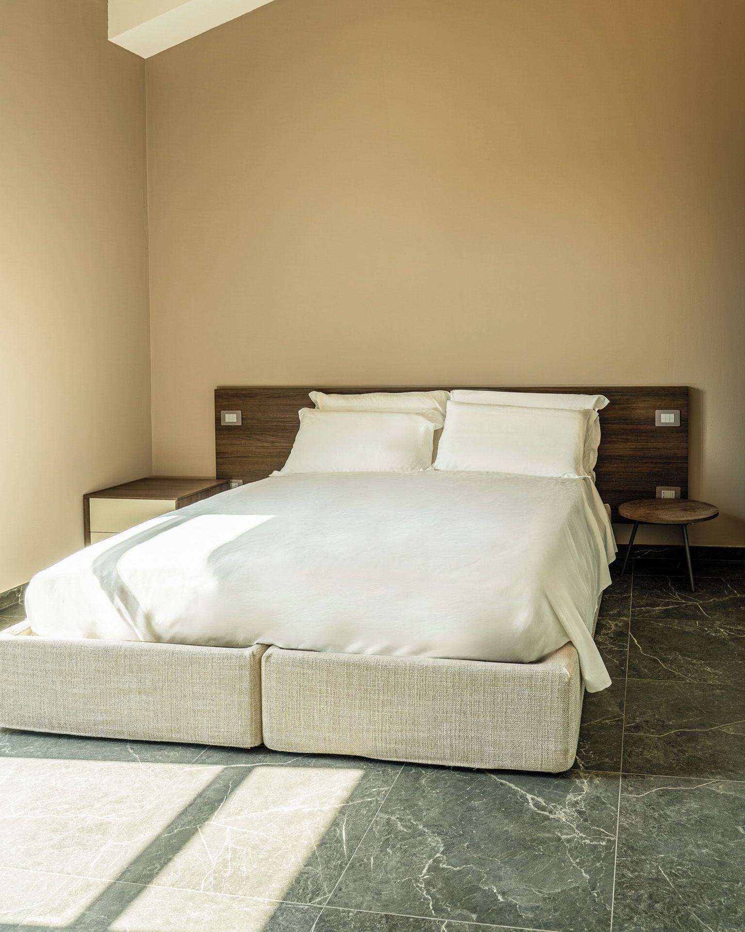 Una habitación de hotel con una cama grande, un cabecero de madera, una mesita de noche y una pequeña mesa redonda.