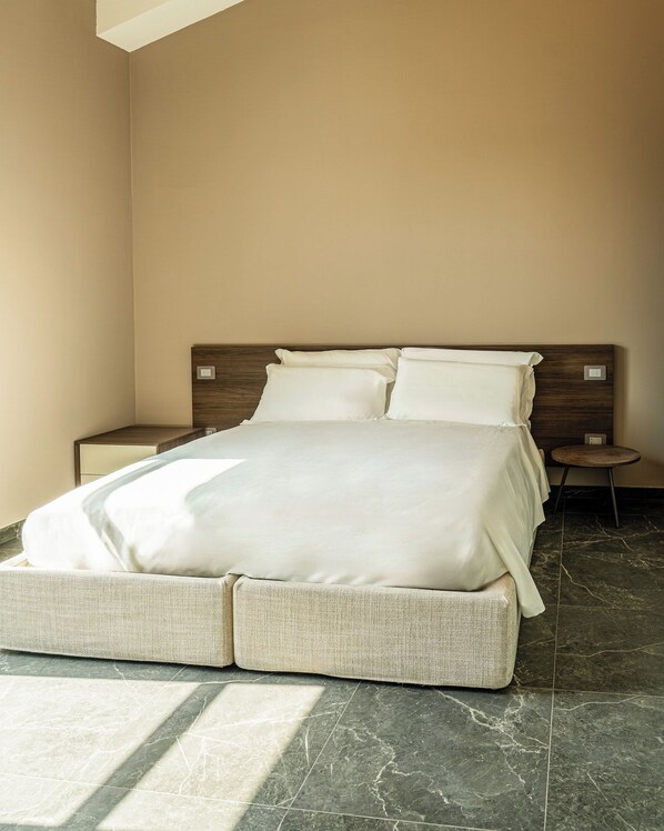 A hotel room with a large bed, a wooden headboard, a nightstand, and a small round table.