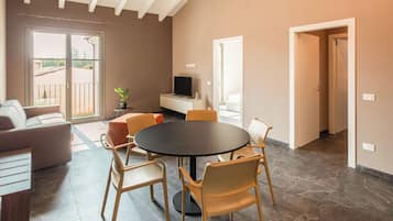 A spacious living area with a high ceiling, a round dining table, and modern furniture.