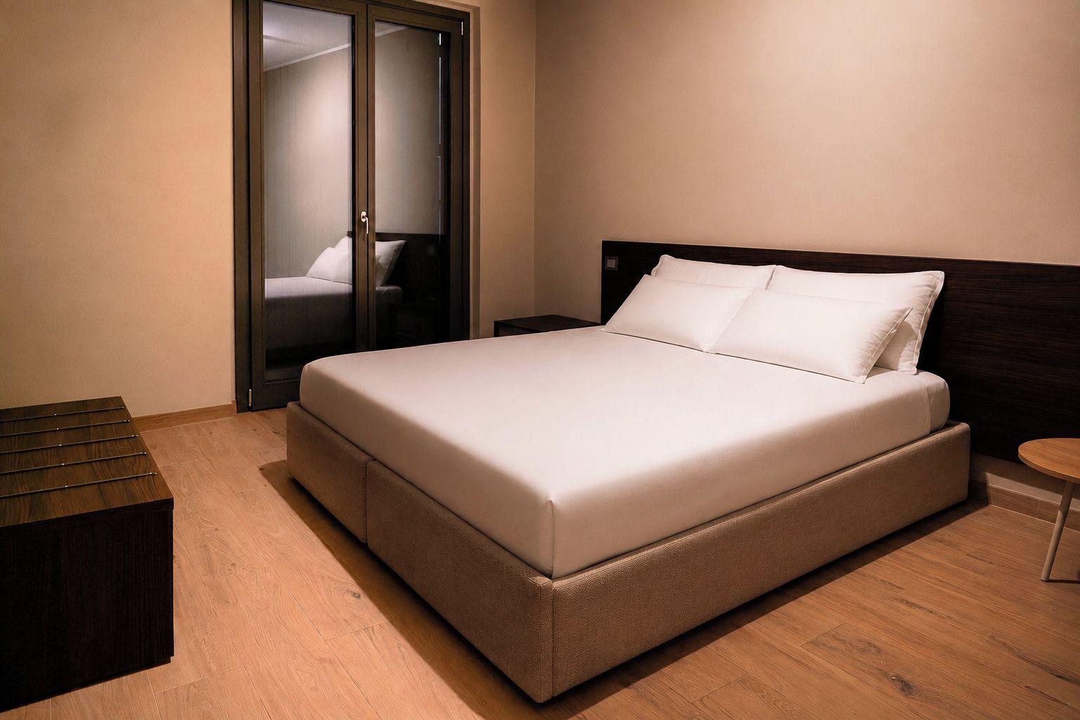 A bedroom with a large bed, a bedside table, a wooden bench, and a wardrobe with a mirror.
