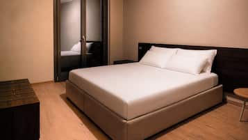 A bedroom with a large bed, a bedside table, a wooden bench, and a wardrobe with a mirror.