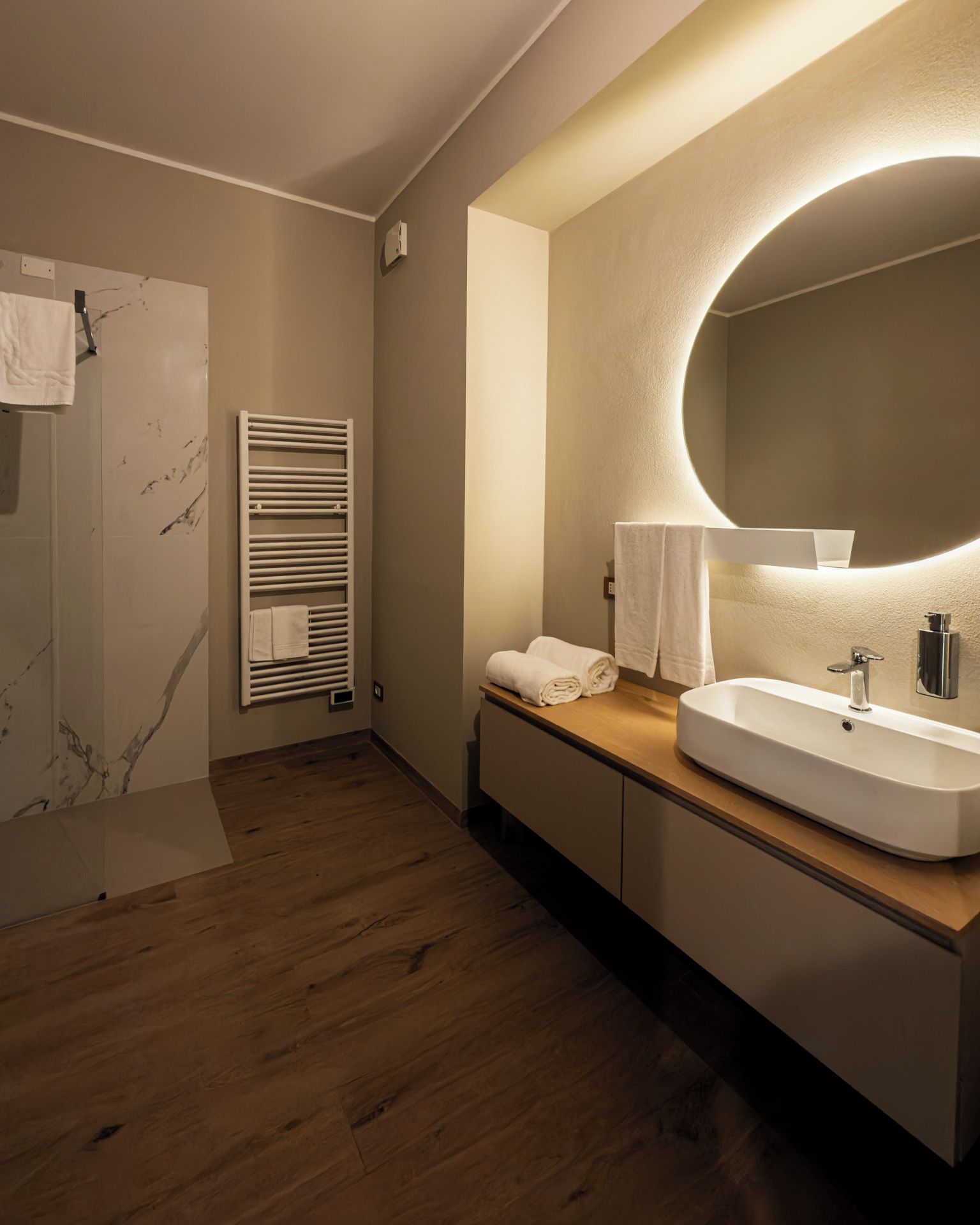 Un baño moderno con tocador de madera, un espejo grande y una ducha integrada.