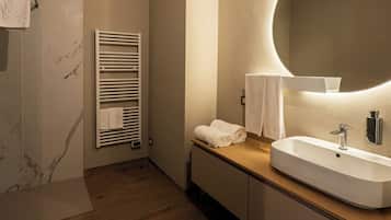 Un baño moderno con tocador de madera, un espejo grande y una ducha integrada.