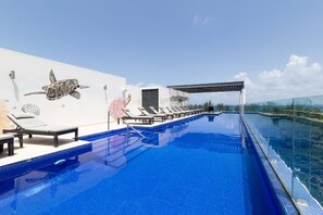 A rooftop infinity pool with lounge chairs and a mural of a sea turtle. - Hidden Away in the Jungle Near the Beach (Playa del Carmen)