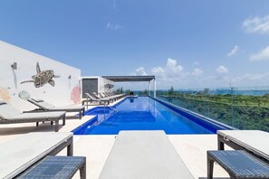 A rooftop infinity pool with lounge chairs and a mural of a sea turtle. - Hidden Away in the Jungle Near the Beach (Playa del Carmen)