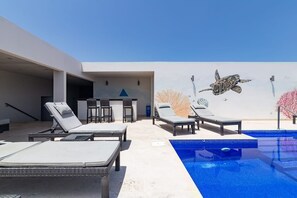 A rooftop pool area with lounge chairs and a mural of a sea turtle. - Hidden Away in the Jungle Near the Beach (Playa del Carmen)