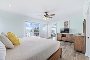 A bedroom with a bed, a ceiling fan, a TV, and a view of the outdoors. - Seascape l Oceanfront l Hot Tub l Game Room (St. Johns County)