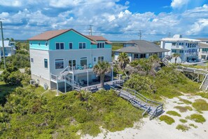 A coastal property with a two-story building, a covered patio, and a staircase leading to a beach area. - Seascape l Oceanfront l Hot Tub l Game Room (St. Johns County)