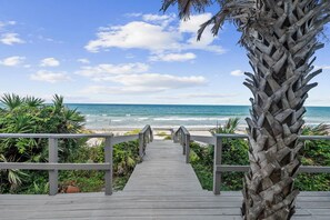 A wooden boardwalk leading to a beach with a clear view of the ocean and a palm tree on the right. - Seascape l Oceanfront l Hot Tub l Game Room (St. Johns County)