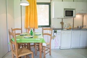 Une cuisine compacte avec un coin repas, équipée d’appareils électroménagers de base et d’une fenêtre.
